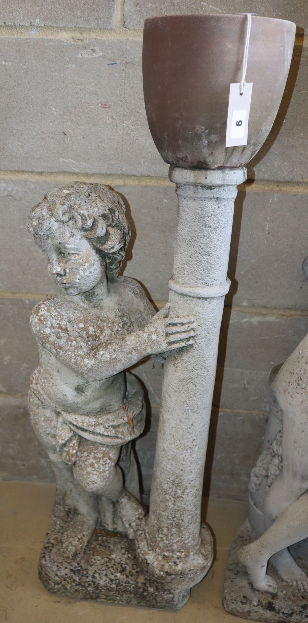 A reconstituted stone garden ornament of a putto beside a pedestal with associated planter, H.92cm